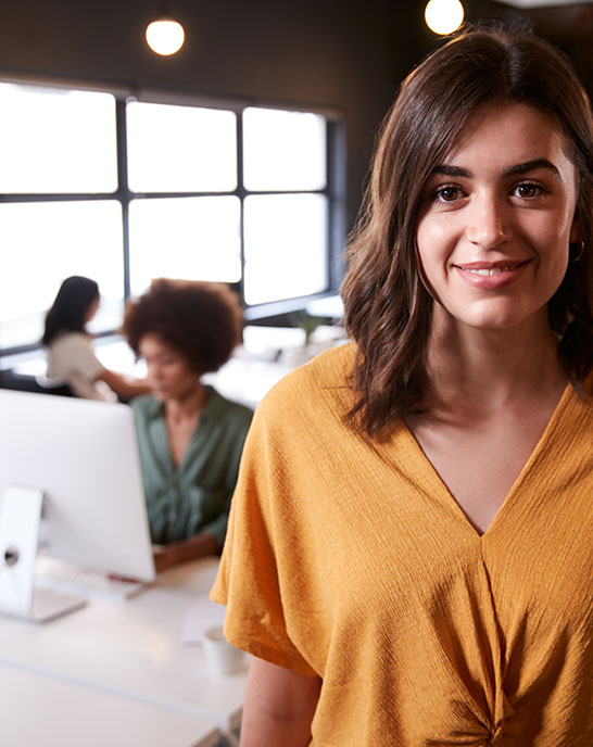 lady looking at the camera and smiling with an office in the background