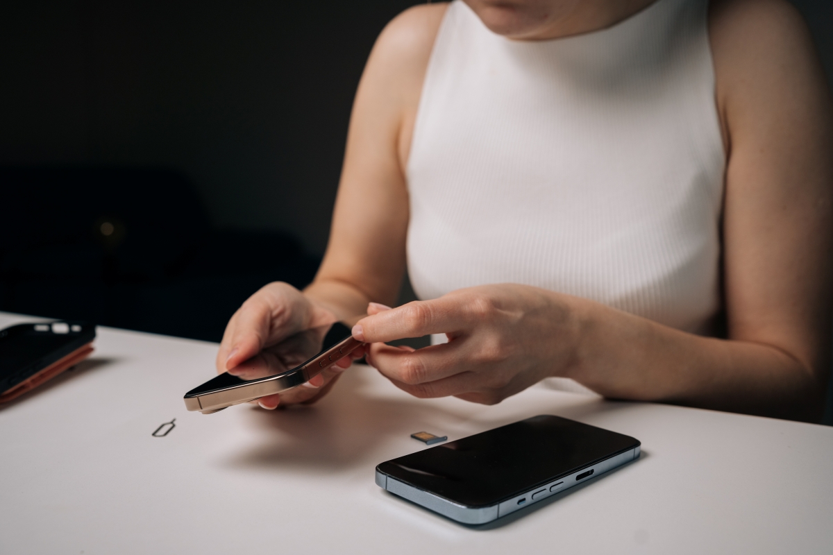 Person sitting at desk inserting a SIM card into a mobile phone