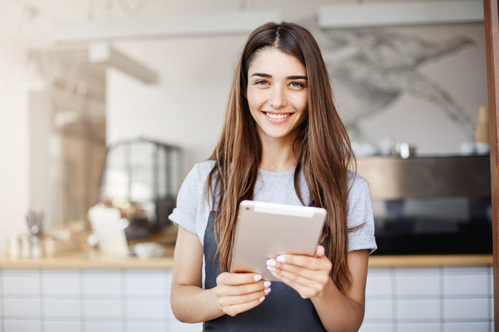 waitress with a tablet smiling at the camera